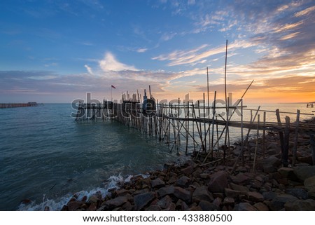 Image of traditional fishermen timber and bamboo jetty known as Langgai during windy sunset.