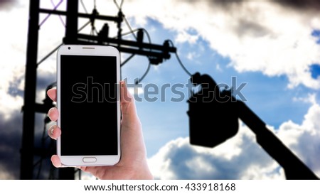 Man use mobile phone, blur image of electrician repair the transmission system before the heavy rain as background.(Back light Silhouette want)