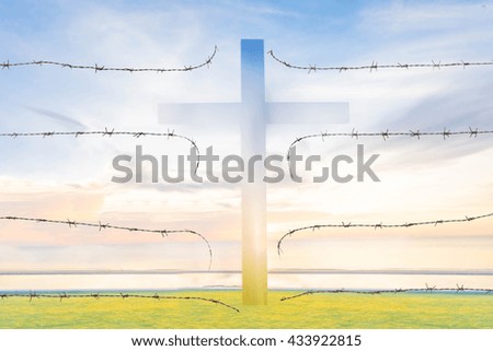 silhouette of broken barb wire fence with cross on sunlight background 