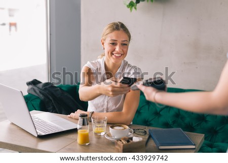 Woman paying contactless with mobile phone in cafe bar Royalty-Free Stock Photo #433929742