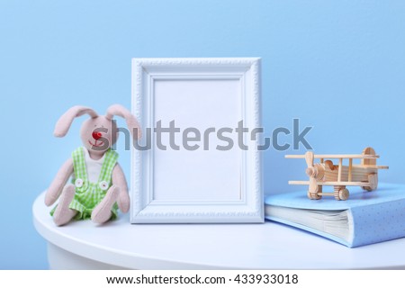 Baby toys and frame on blue wall background