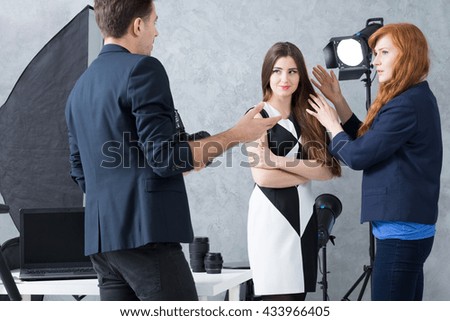Photographer talking to a set manager during a fashion session with a model in a black and white dress