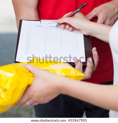 Close-up of a woman signing document of delivered package