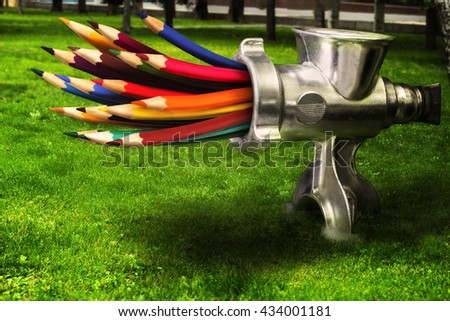 Photo merge  - meat grinder grinds colored pencils on a green lawn.