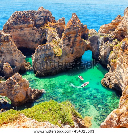 Ponta da Piedade - unique rock formation in the ocean - two boats with tourists visiting famous grottoes. Number one attraction in Lagos, Algrave, Portugal Royalty-Free Stock Photo #434023501