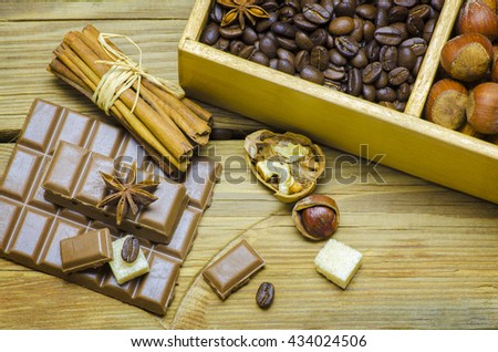 Still life with delicious chocolates placed with cinnamon sticks,nuts,coffee beans and sugar on a wooden table,top view