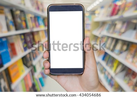 Man hand holding mobile smart phone , tablet,cellphone over Blur Shop Background in Book store Shelf Natural bokeh out of focus Bookstore,Blur background of people in library,book store.vintage photo