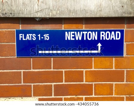 Sign on a wall for Newton Road and direction for Flats 1-15