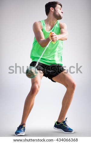 Sportsman throwing a hammer against grey background