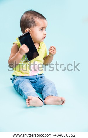 Cute little Indian/asian infant baby girl  using smartphone and calling mother while sitting isolated over white background