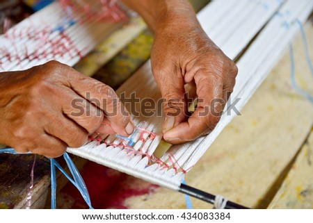 Thai woman hand weaving silk being used to make cloth Royalty-Free Stock Photo #434083384