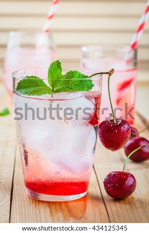cherry lemonade with ice in glasses on a wooden table wooden table