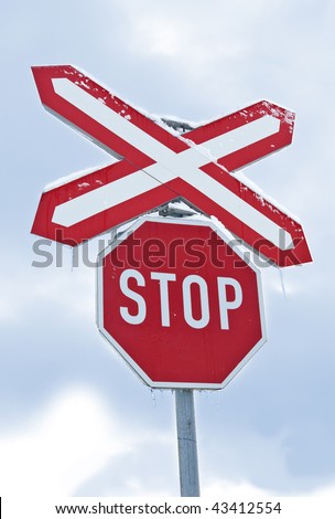 Traffic sign of "Stop" in front of the railway. Small icicles are visible