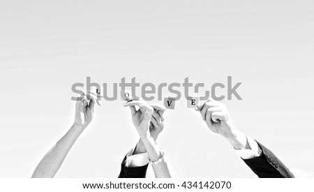 Hands of bride and groom keeping letters LOVE, black and white photo. Man and woman on weddings day, body part photo, marriage, word LOVE