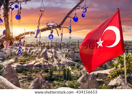 Evil eyes, balloon and Turkish flag on the tree in Goreme panorama at sunset sky Cappadocia, Turkey