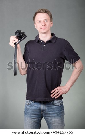 Young funny guy holding retro style camera isolated on grey background