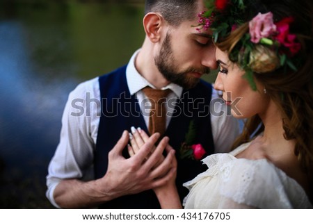 the groom in a wedding suit and the bride in lace dress with bouquet and wreath in the forest Royalty-Free Stock Photo #434176705