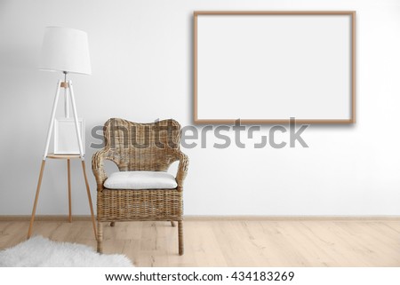 Cozy chair with lamp and empty picture frame on wall background