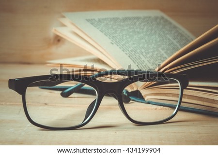 Old books and glasses on a wooden table with filter effect retro vintage style