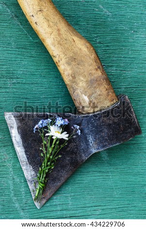 Beautiful bouquet of flowers covering the old rough ax. Bury the hatchet. Royalty-Free Stock Photo #434229706
