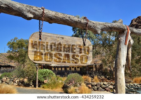 old vintage wood signboard with text " welcome to Bosaso" hanging on a branch