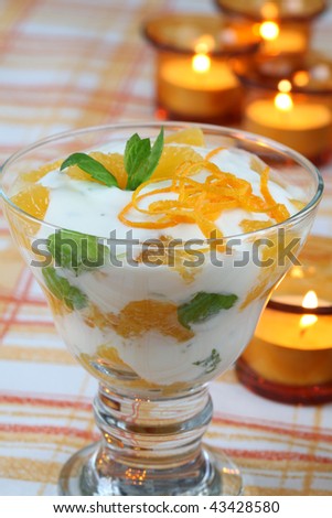 Mint yogurt dessert with oranges and candles in background