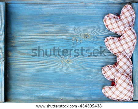 Wooden background with handmade textile hearts on old wooden plank. Blue color. Rustic design