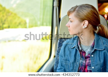 Young tourist girl looking through the window in high-speed train