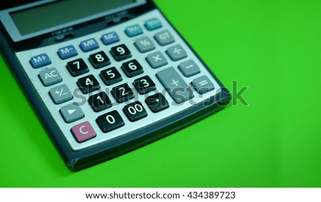 A part of calculator on green background,blurred