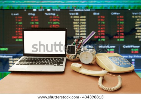 laptop and telephone with blur graph stock market background