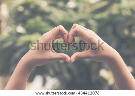 Hand on heart-shaped bokeh background blurred, natural tones vintage style. Show the world you love Love Family between two people.Let's Stay Together happy mother's day, Royalty-Free Stock Photo #434412076