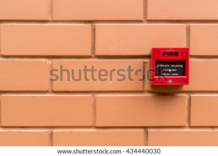 Red fire switch on brown brick wall