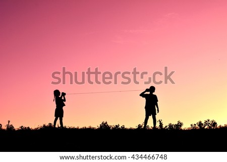 Silhouette of children playing string phone at the sky sunset Royalty-Free Stock Photo #434466748