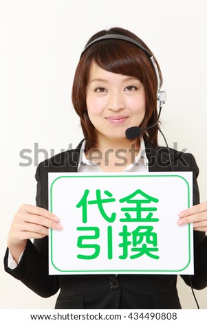 young Japanese businesswoman holding a message board with the phrase cash on delivery in KANJI