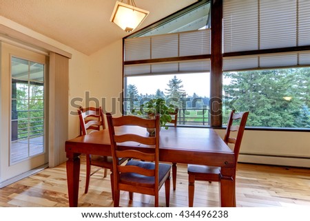 Simple dining room interior with vaulted ceiling,  large windows and hardwood floor.