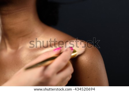Close up portrait of beautiful Afro American girl's bare shoulder with a powder brush