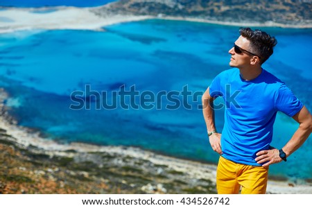 man reluxing on a rock against a blue sea