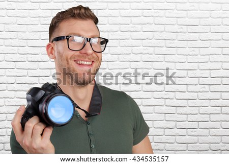 Portrait of a handsome young in glasses man with camera