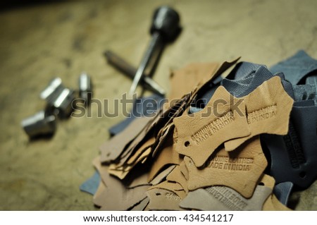 Made In India Leather Embossing with embossing tools. Leather labels, embossed with genuine leather and Made in India are in sharp focus, but embossing tools are in the background. 
 Royalty-Free Stock Photo #434541217
