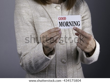Good Morning. Businesswoman holding a card with a message text written on it
