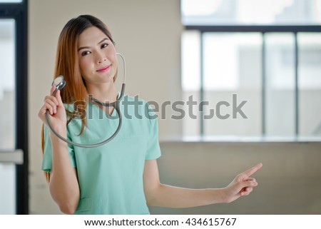 Happy smiling young beautiful female doctor showing blank area for sign or copyspace