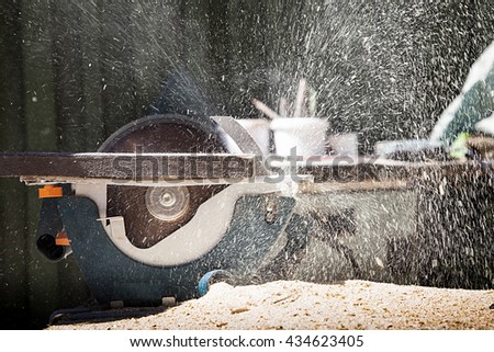 someone cutting wood with electric saw. Sawdust flying in the sky Royalty-Free Stock Photo #434623405
