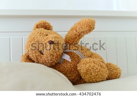 Lonely Teddy Bear lying on the bed. Concept about waiting for someone and loneliness. (Focus on bear's eye)