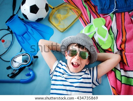 boy with sunglasses and toys on blue blanket