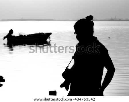 Silhouette of  a person with camera at the beach - black and white