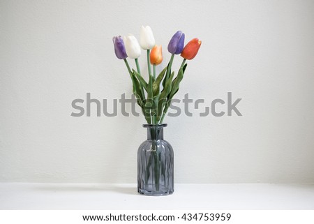 6 TULIPS in a glass vase against the wall