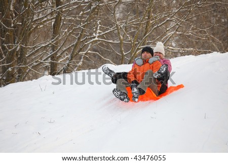 Young couple having fun in winter by sliding down hill