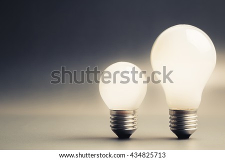 Comparative big and small light bulb, small and medium sized business, coaching, training, or other comparison concept Royalty-Free Stock Photo #434825713