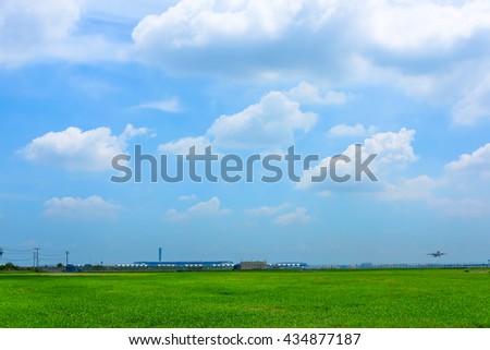 Field of green grass near the airport and sky and clouds background