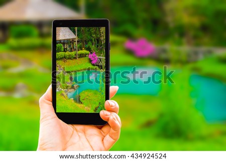 Woman hand holding smart phone show a photo of garden of hot spring at Jae son national,Thailand.